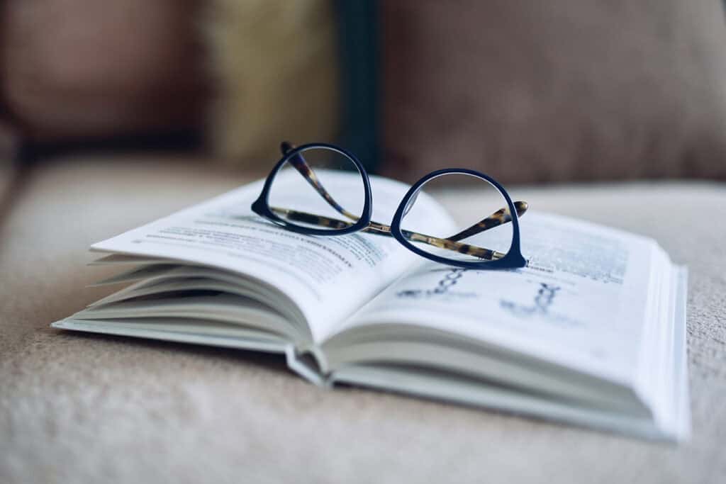 Glasses and book on couch to represent Mesa's reading list.Soft focus glasses, book on the sofa. Abstract book blur background.