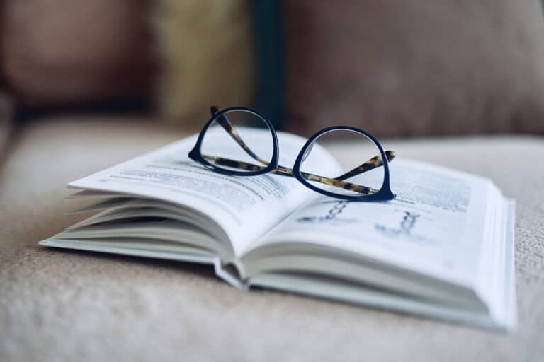 Glasses and book on couch to represent Mesa's reading list.Soft focus glasses, book on the sofa. Abstract book blur background.