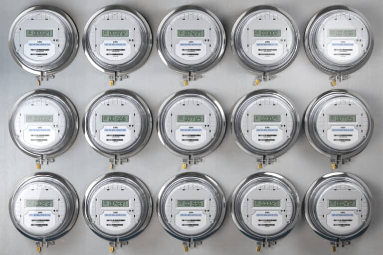 Digital electrical meters lined up in rows and columns, measuring power use.