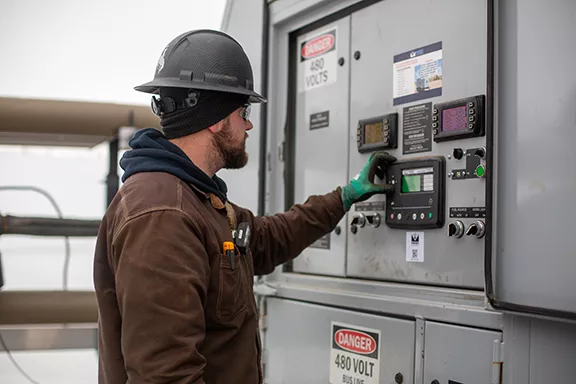 Mesa Power Solutions Senior Technician adjusting the control panel on a generator in North Dakota.