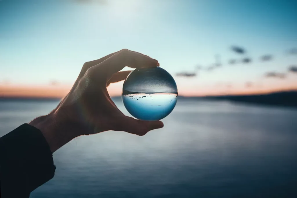 Selective focus to help with mindfulness is shown with a ice cube sphere and a lake and hills in the background.