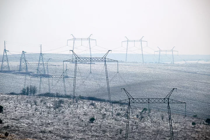 Steel pillar of high voltage electric power lines delivering energy with a dense fog in the background.
