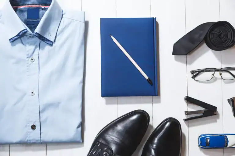 Professional, outfit idea of businessman attire with notebook and pen on a white wooden background.