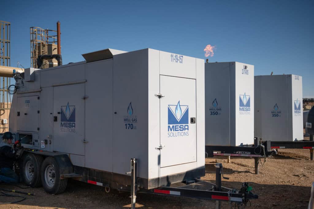 Mesa Power Solutions generator units operating at an industrial site under clear skies, representing dependable mobile energy systems, advanced engineering, and reliable power performance in the field.